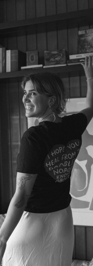 Lotta Falter trägt ein T-Shirt mit der Botschaft ‚I hope you heal from all the things nobody knows about‘. Lotta Falter von hinten, trägt ein schwarz-weißes T-Shirt mit dem Schriftzug ‚I hope you heal from all the things nobody knows about