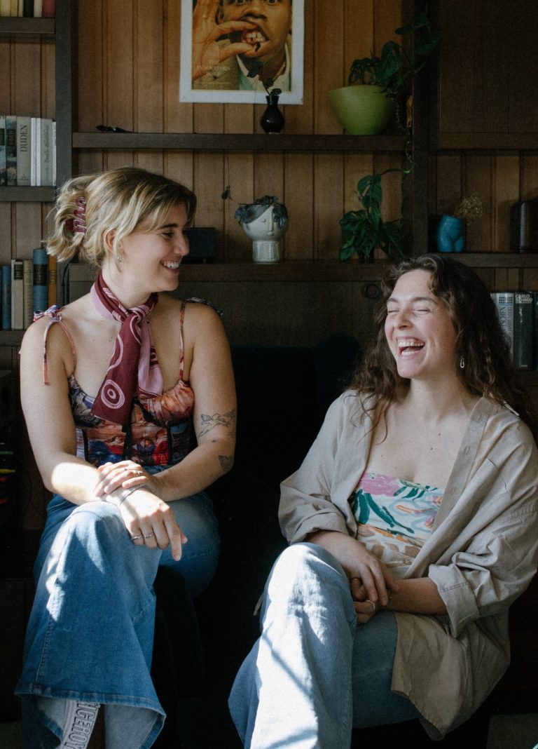 Lotta Falter und Lisa Schubert im Gespräch Lotta Falter und Lisa Schubert, systemische Therapeutinnen in Mannheim, sitzen an einem Tisch und lachen